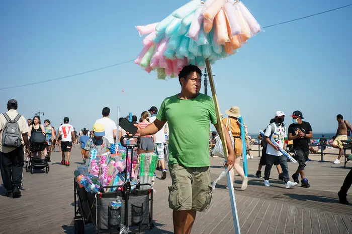 a man sells cotton candy on a boardwalk